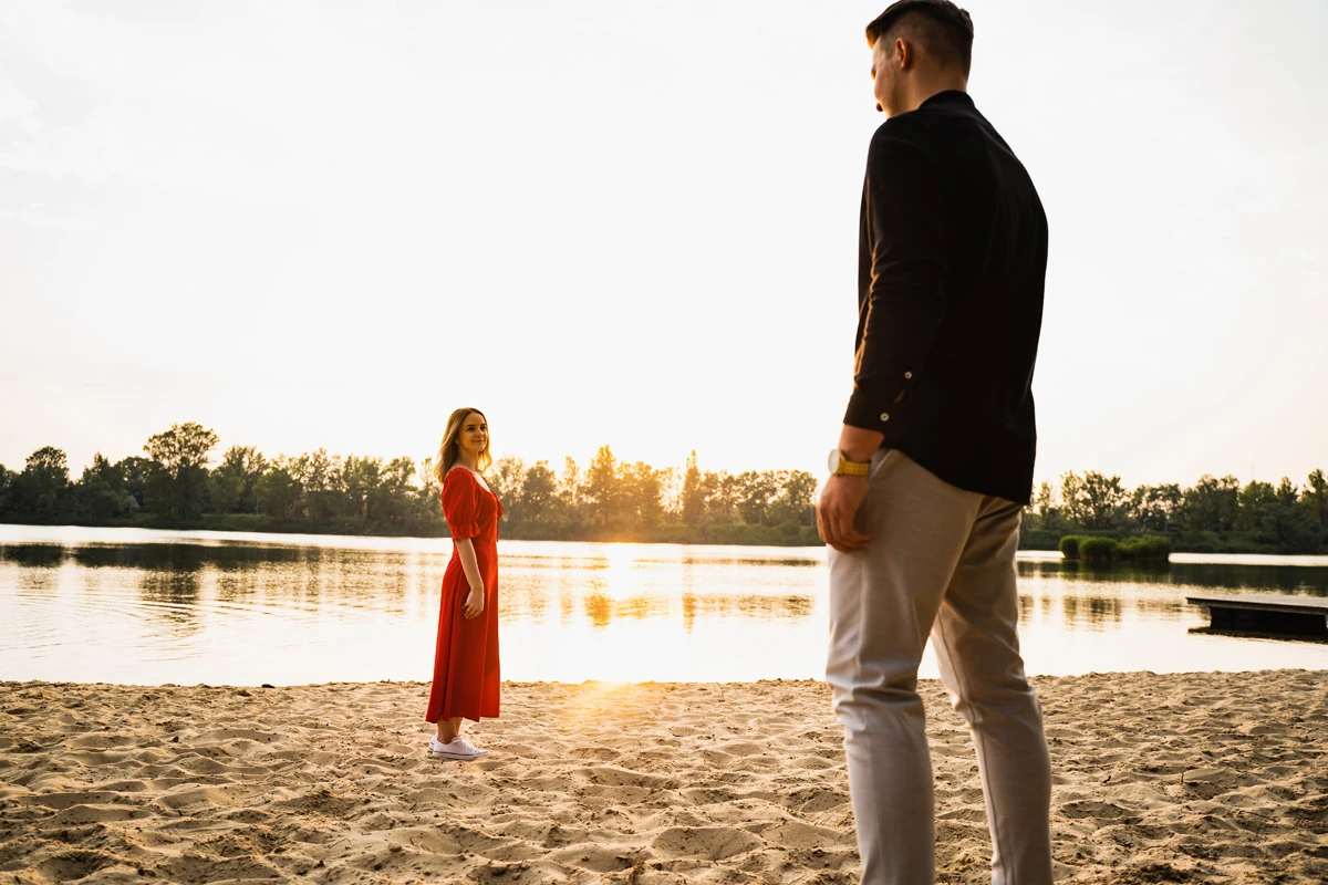 para zakochanych podczas sesji narzeczeńskiej na piaszczystej plaży nad jeziorem w świetle zachodzącego słońca
