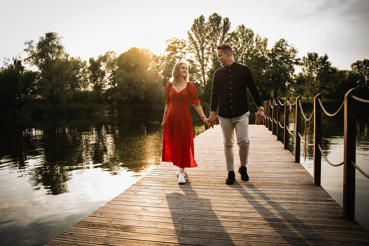 Zakochana para spacerująca po drewnianym pomoście nad jeziorem o zachodzie słońca